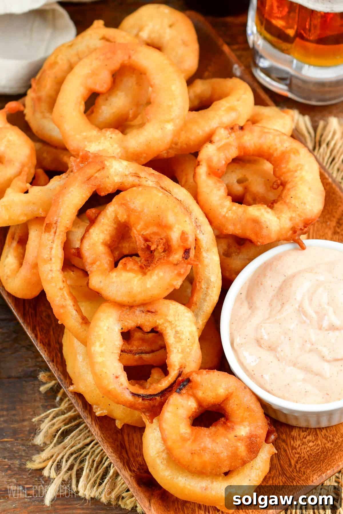Beer Battered onion rings on a plate with dipping sauce in a a small bowl.