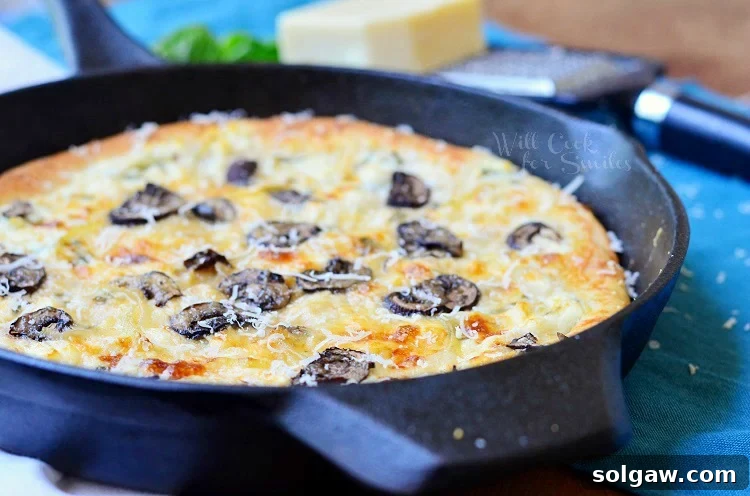 Close-up of Asiago Mushroom & Onion White Skillet Pizza baking in a cast iron skillet, showcasing golden crust and melted cheese