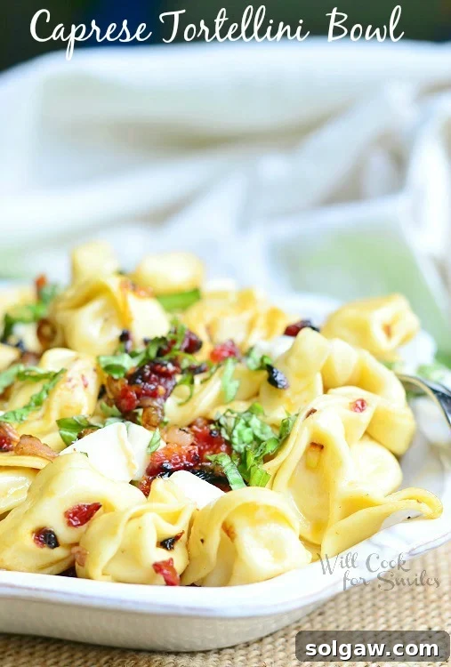 Caprese Tortellini on a white plate, highlighting fresh tomatoes, mozzarella, and basil.