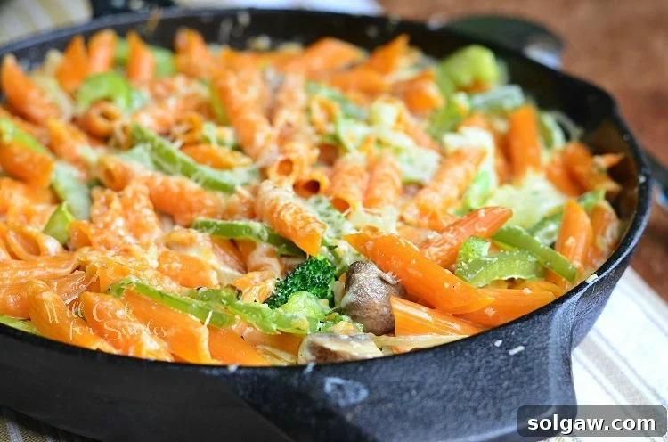 Horizontal photo of Pasta Primavera in a cast iron skillet, showing a generous serving.