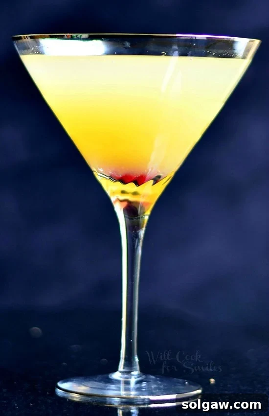 Pineapple Champagne Martini in a martini glass with a cherry in the bottom, beautifully arranged.