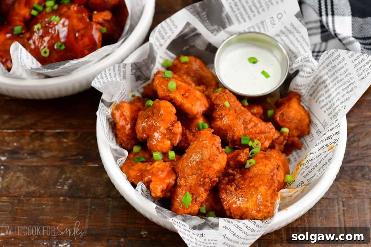 Crispy Chicken Bites 6 several buffalo sauce boneless wings in a bowl with a side of ranch dressing.