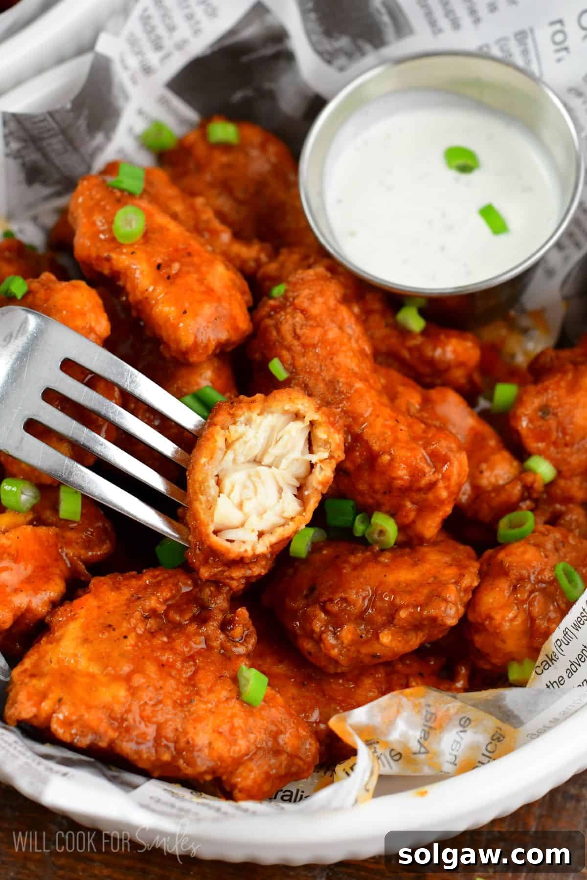 Crispy Chicken Bites 8 boneless wings in buffalo wing sauce in a bowl with one bite taken out of one wing.
