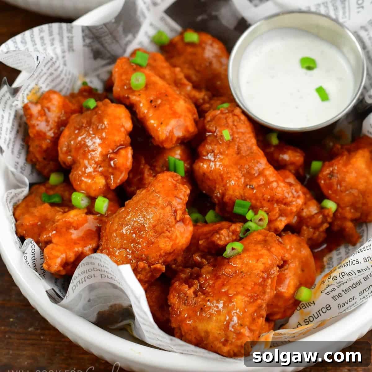 Crispy Chicken Bites 9 boneless buffalo wings in a plate lined with newspaper food liner.