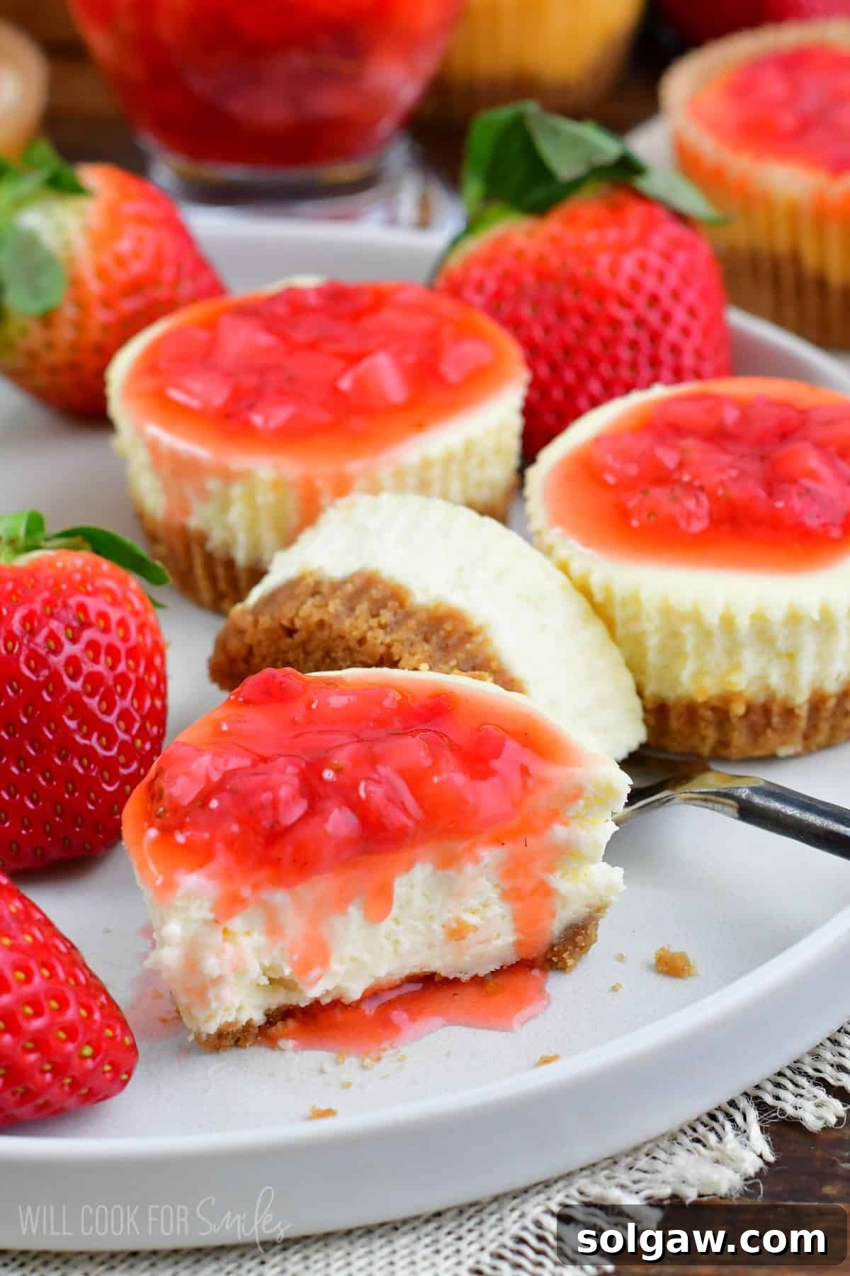 one of the mini cheesecakes cut in half next to the other half and more cheesecakes.