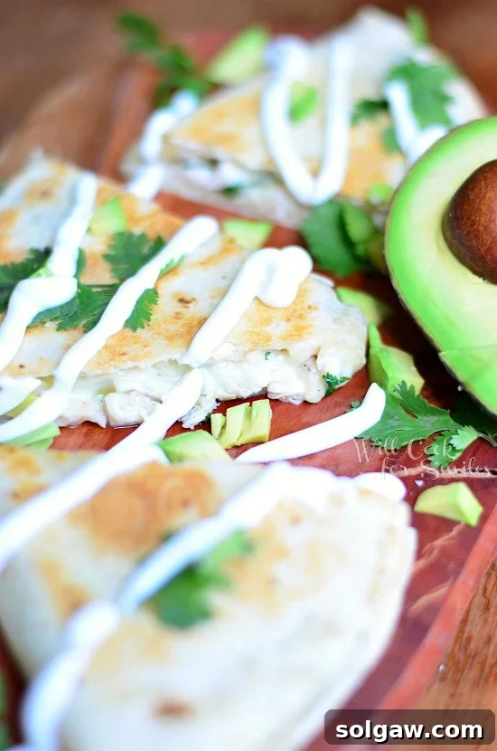Close-up shot of an Avocado Chicken Quesadilla resting on a wood cutting board, ready to be served.