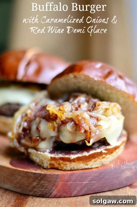 Gourmet Buffalo Burger on a bun with rich Caramelized Onions and savory Red Wine Demi Glace, served on a rustic wood cutting board.