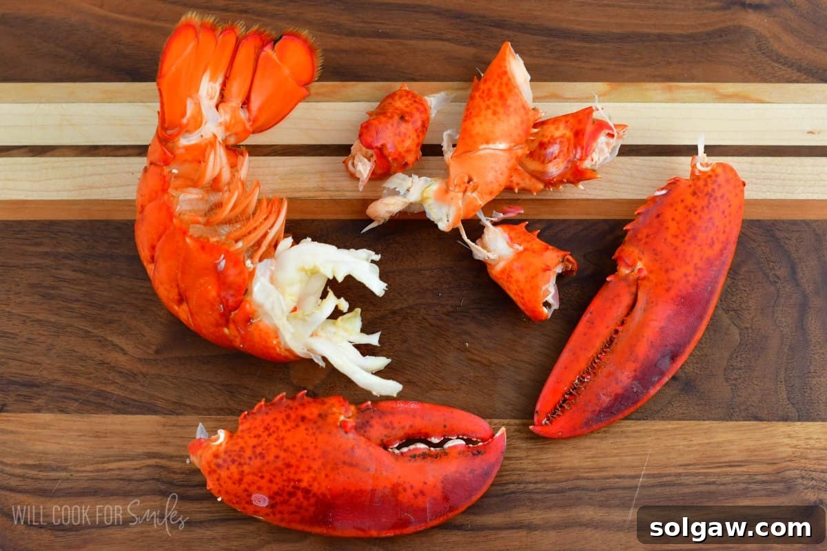 Unlock the Flavor: Perfect Lobster Every Time 7 Various cooked lobster parts—claws, knuckles, and tail—laid out on a wooden cutting board before the meat is fully extracted.