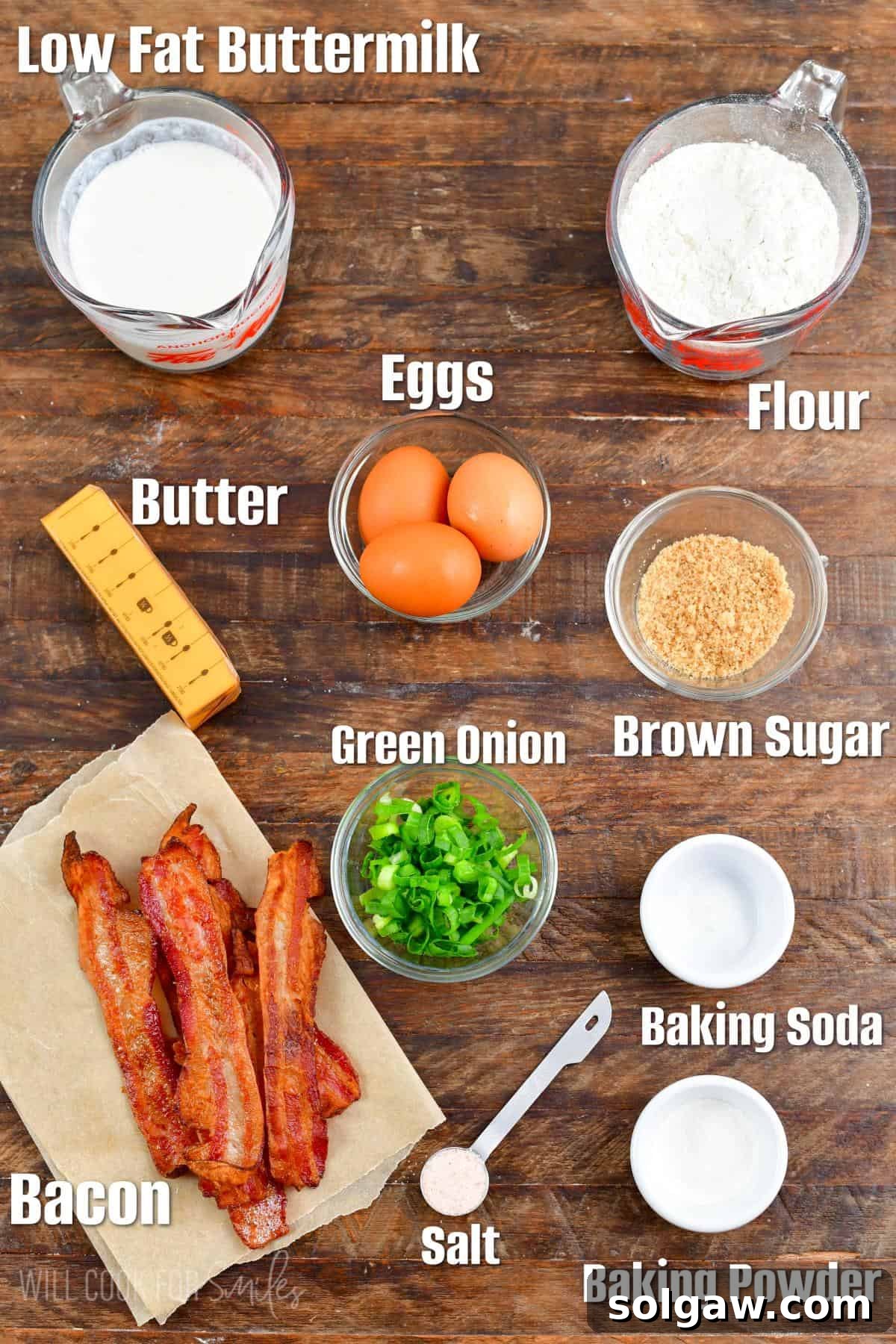 Labeled ingredients for savory waffles on a wood surface, showcasing fresh eggs, buttermilk, and chopped green onions.