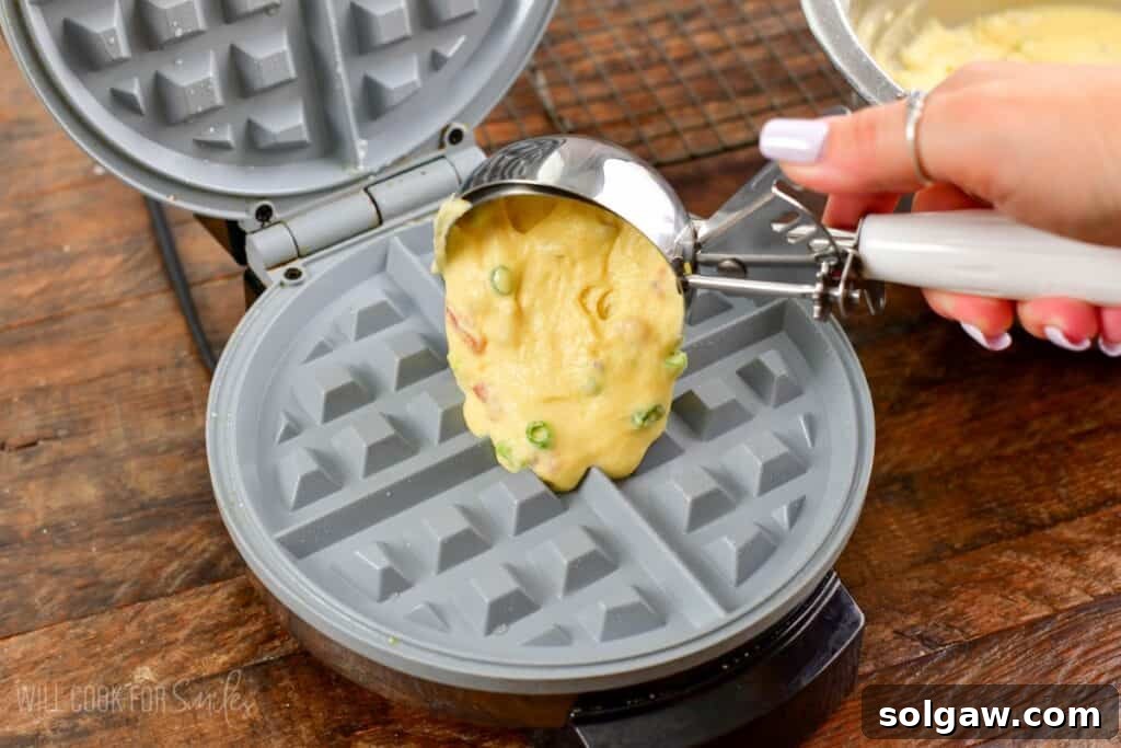 Using an ice cream scoop to scoop waffle batter into waffle maker.