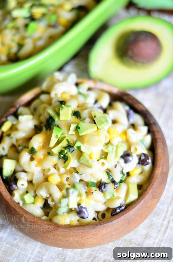 Tex-Mex Mac and Cheese in a wood bowl with an avocado to the top right