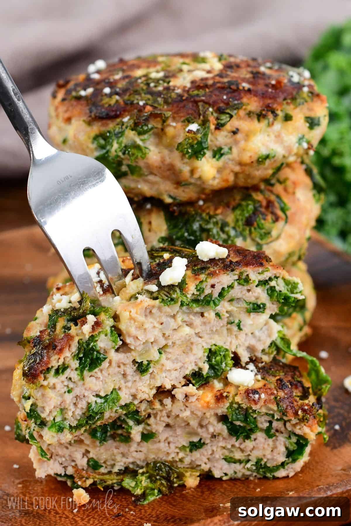 A perfectly cooked Kale and Feta Turkey Burger, cut in half and stacked, revealing the juicy interior with visible kale pieces and melted feta.