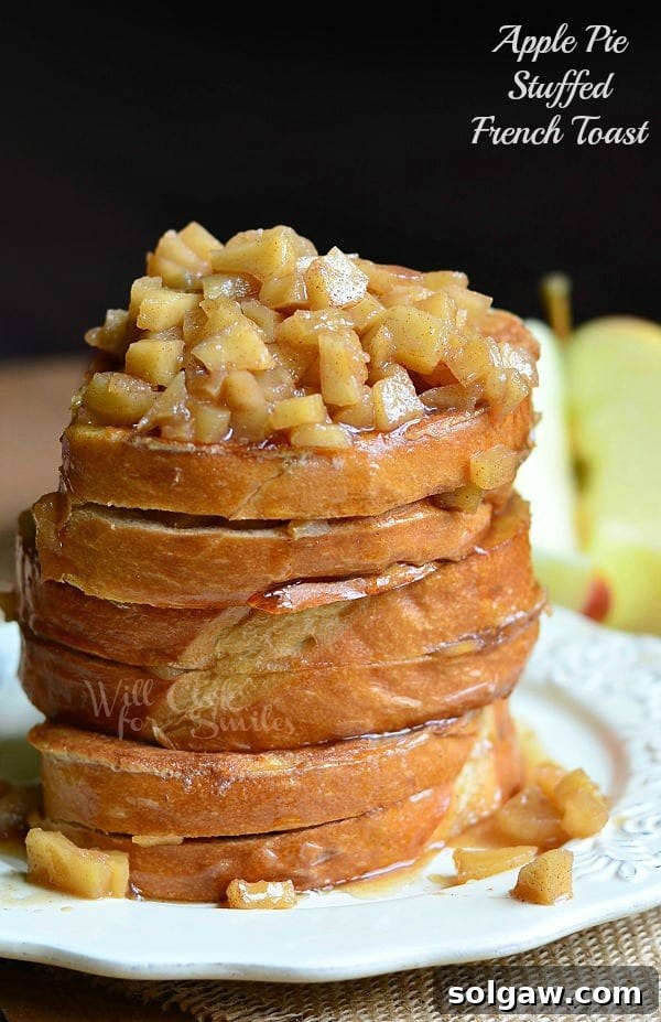 Spiced Apple Pie French Toast 2 Stacked Apple Pie Stuffed French Toast with warm apple pie filling and a drizzle of syrup on a white plate