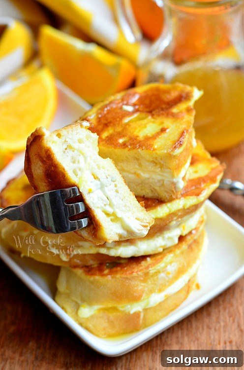 Spiced Apple Pie French Toast 14 Orange Creamsicle French Toast on a plate with a fork and a bite taken, surrounded by oranges and syrup