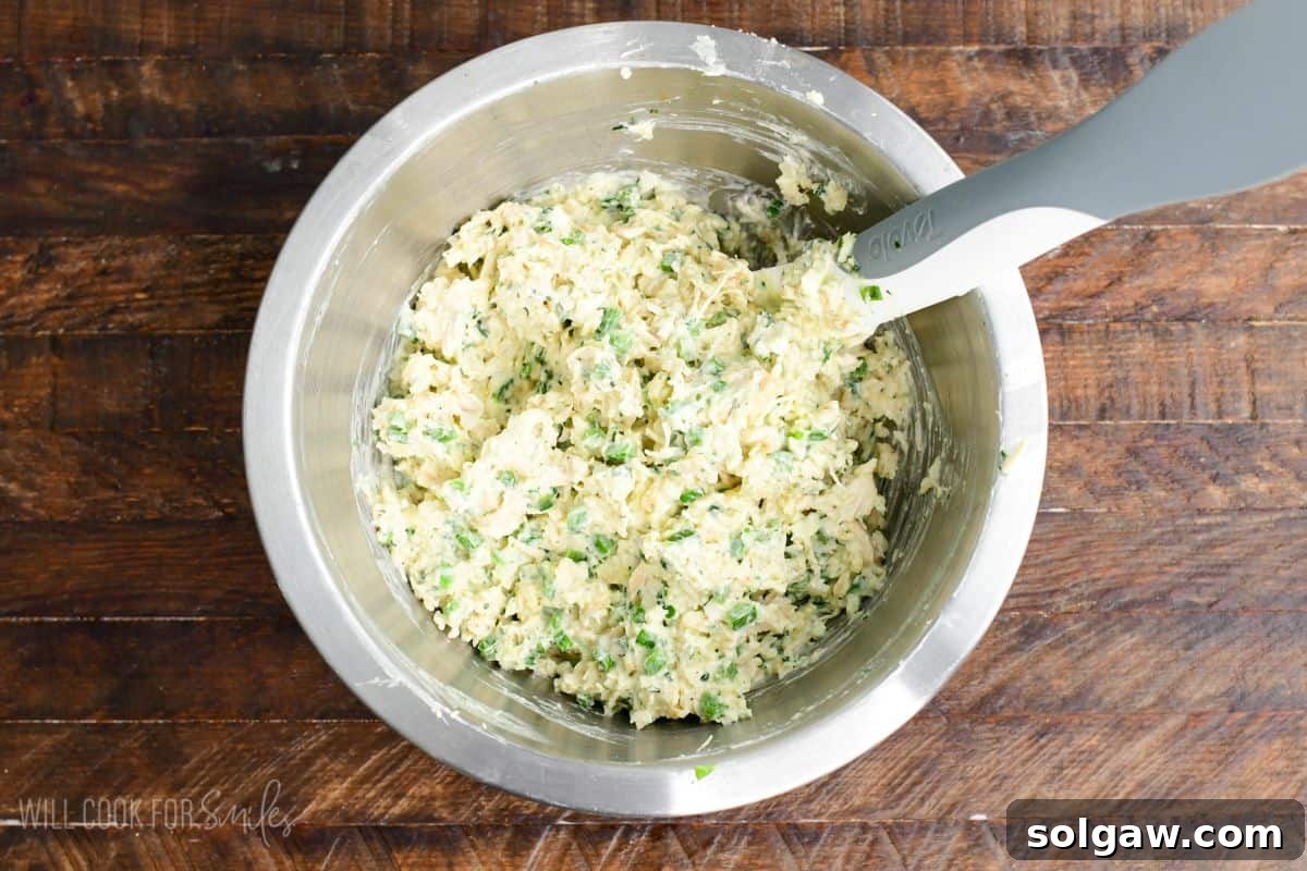 Creamy jalapeño ranch chicken filling mixed in a bowl on a wood surface, ready for assembly.