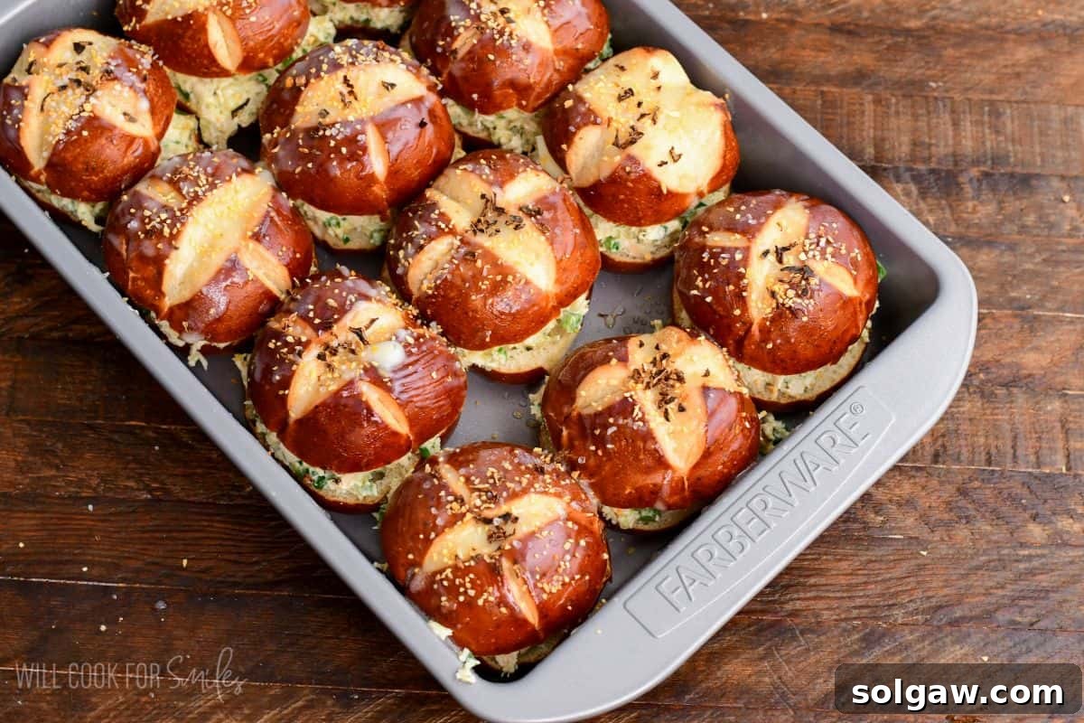 Assembled jalapeño ranch chicken sliders on pretzel buns arranged neatly in a baking dish and seasoned before baking.