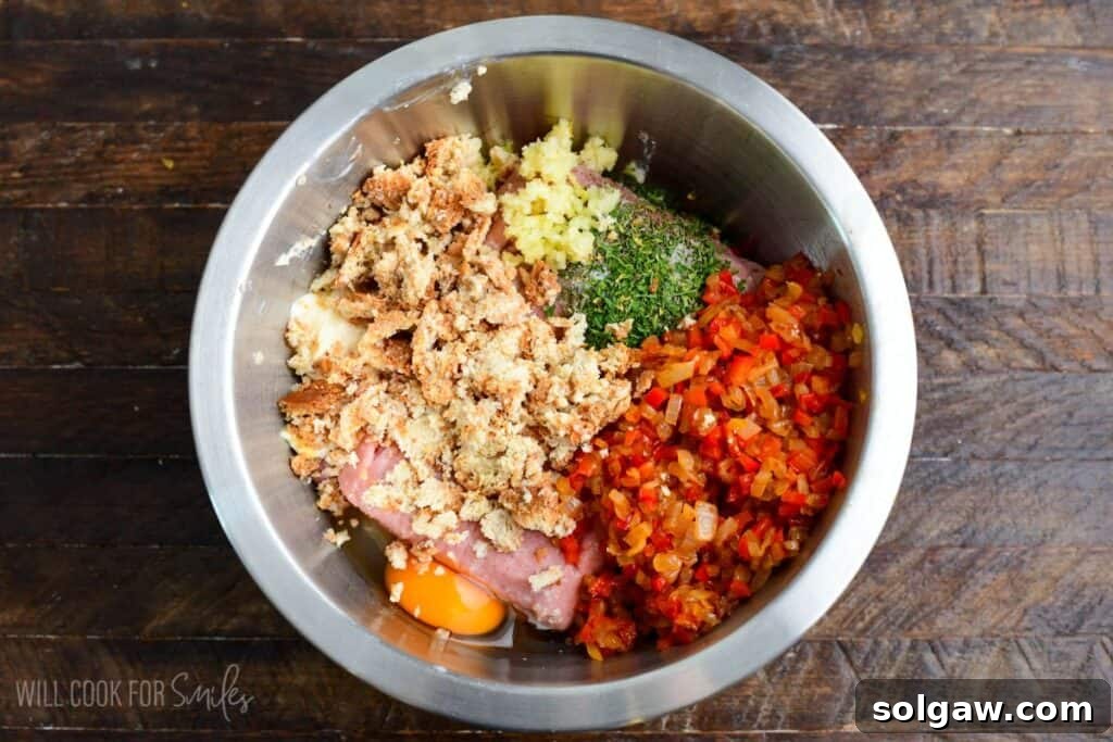 Ground turkey, sautéed peppers and onions, egg, breadcrumbs, garlic, and herbs combined in a mixing bowl to prepare turkey meatloaf.