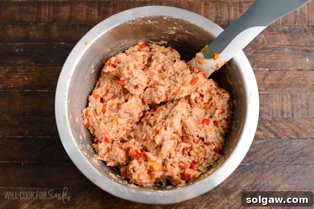 Turkey meatloaf mixture fully combined in a mixing bowl, showing ground turkey blended with diced peppers, onions, breadcrumbs, egg, and herbs before shaping.