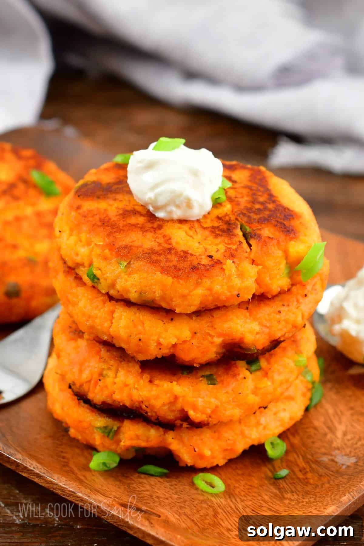 A stack of sweet potato cakes is topped with a dollop of sour cream. 