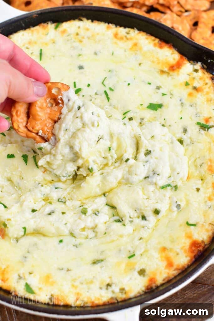 scooping gooey baked four cheese dip from a skillet, perfect for parties and gatherings.