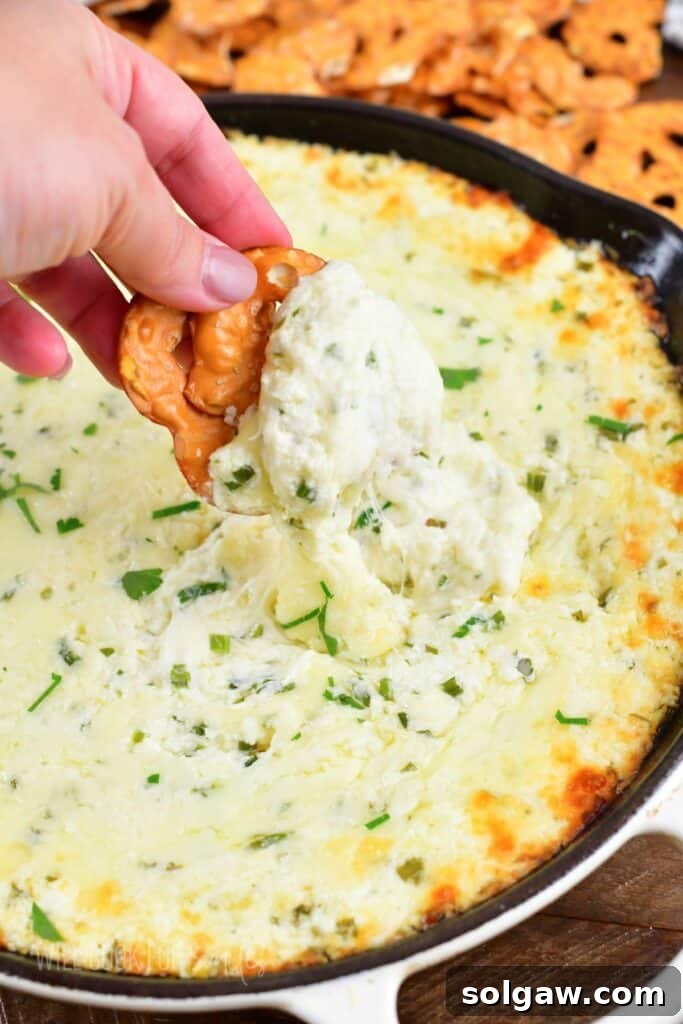 dipping a pretzel chip into the warm, gooey baked four cheese dip.