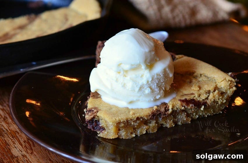 Dreamy Vanilla Bean Swirl Skillet 4 A serving of Vanilla Bean Marble Skillet Cookie on a plate, topped with a generous scoop of melting vanilla ice cream, creating a delightful contrast.