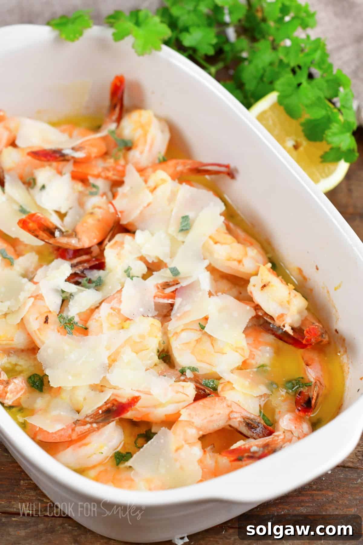 Shrimp baked in garlic and butter in white baking dish.