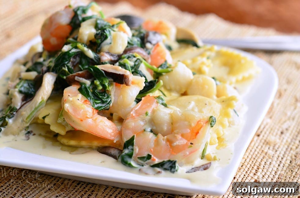 White decorative plate with ravioli with seafood spinach mushrooms in garlic sauce on a tan placemat on a wooden table with a spoon in the background.