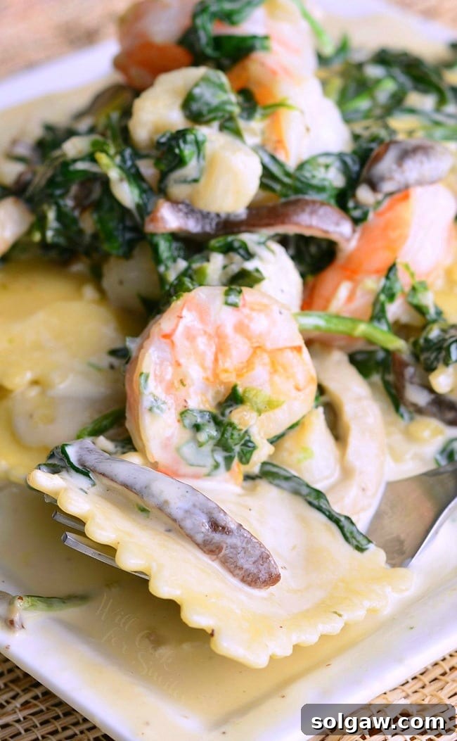 A close-up shot of a white plate filled with Seafood Ravioli, displaying the creamy sauce and a mix of shrimp, scallops, spinach, and mushrooms, ready to be served.