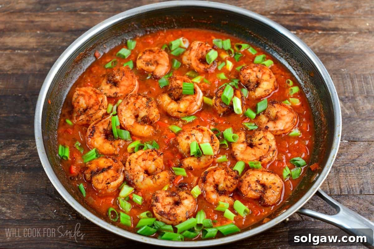 Bayou Shrimp and Rice 5 Cajun shrimp simmering in a rich sauce in a pan, garnished with fresh green onions, ready to be served.