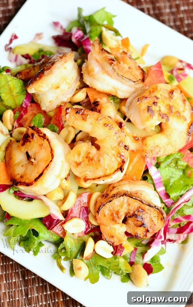 Zesty Thai Shrimp Salad with Creamy Peanut Dressing 3 Overhead view of a beautifully arranged Thai Shrimp Salad with Peanut Dressing on a white plate, showcasing the colorful vegetables and golden shrimp