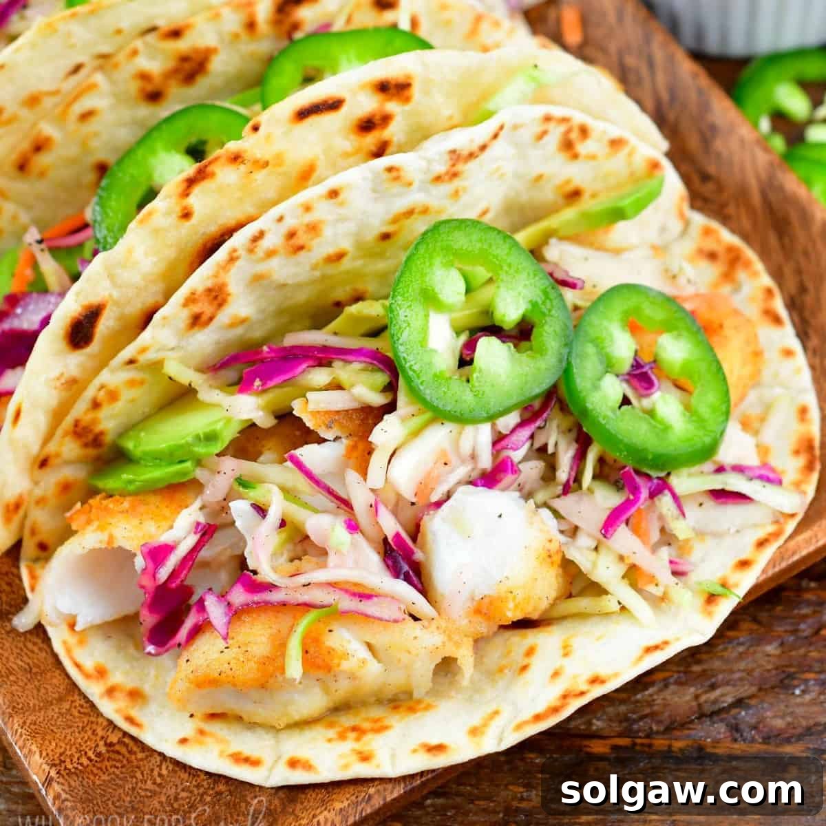 one fish taco topped with colorful slaw and jalapenos.