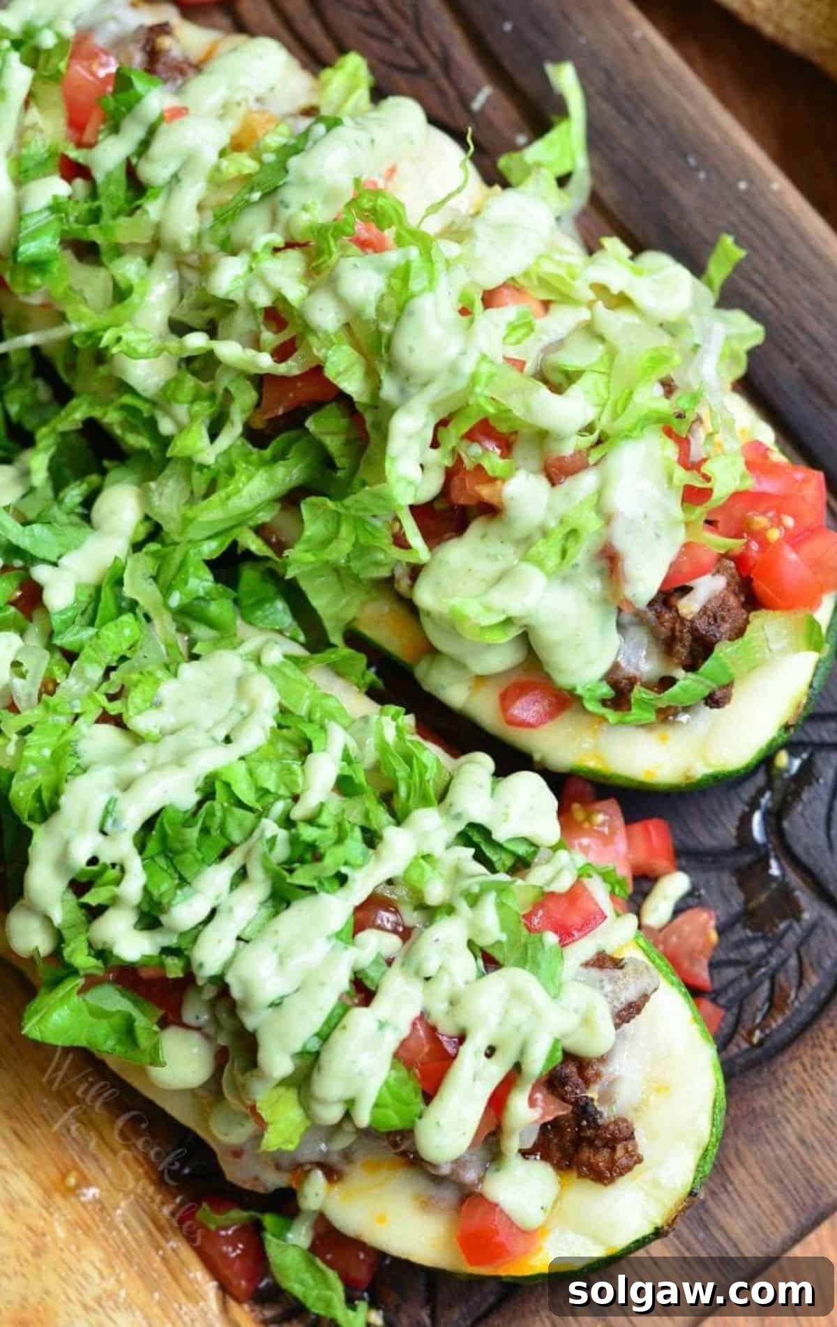 Two vibrant Taco Zucchini Boats, garnished with fresh toppings, resting on a rustic wooden surface.
