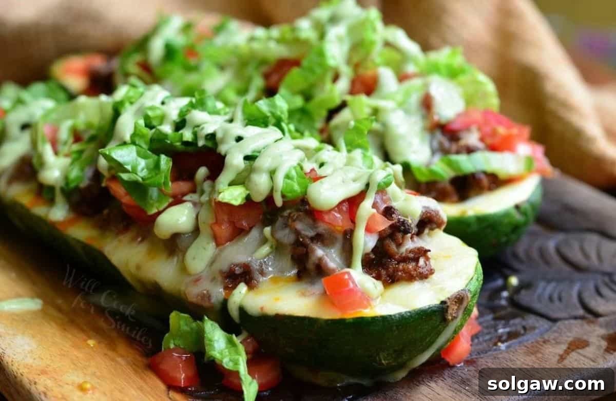 Two beautifully garnished Taco Zucchini Boats presented on a wooden board, ready to be enjoyed.