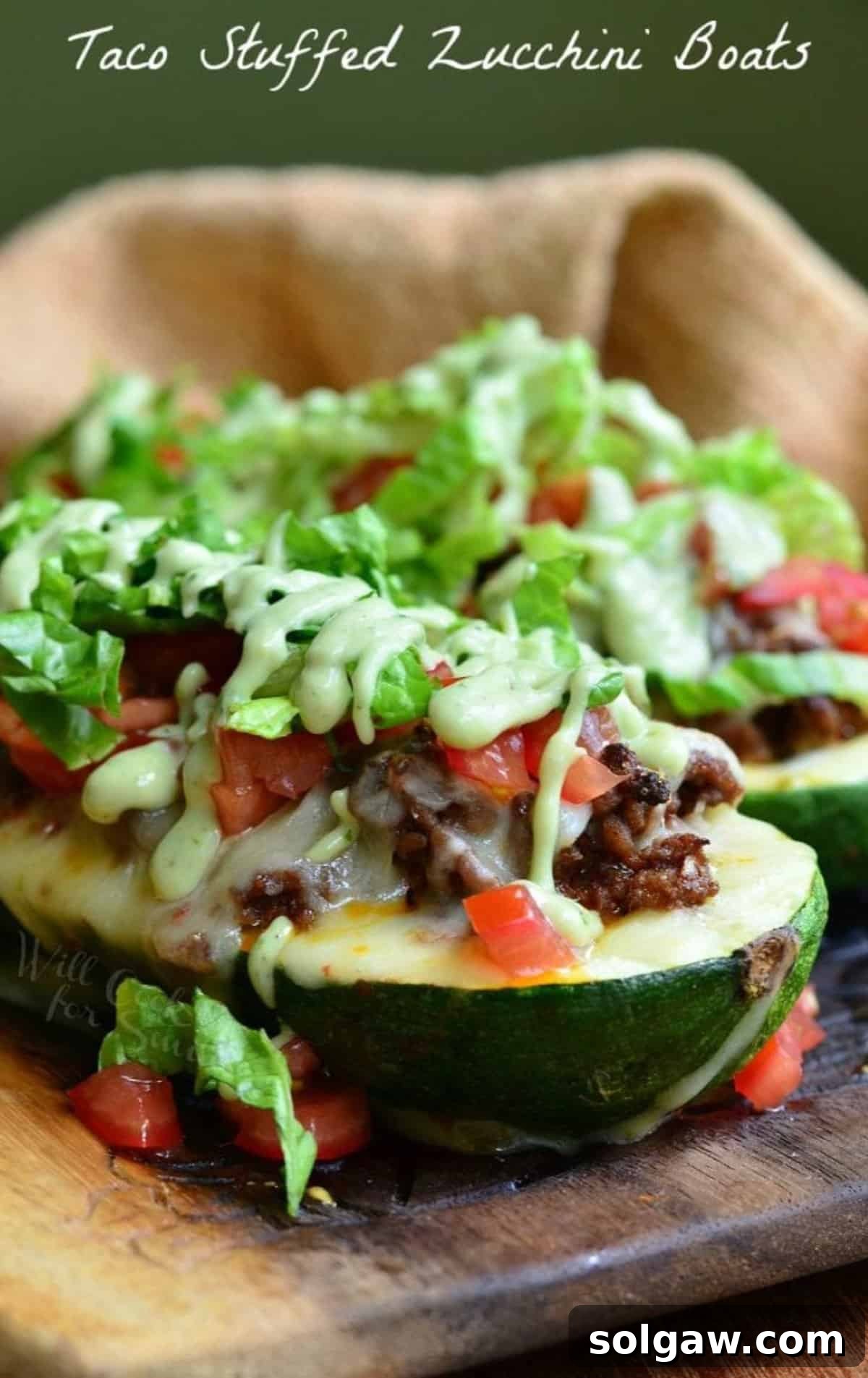 A large zucchini boat generously stuffed with beef and topped with crisp lettuce, diced tomatoes, and a creamy dressing.