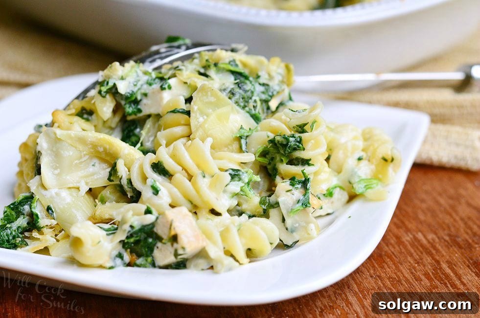 A serving of the Chicken Spinach and Artichoke Pasta Casserole on a white plate.