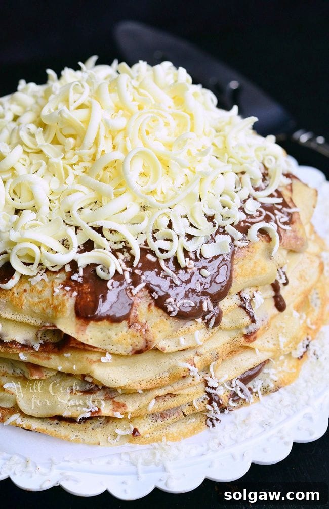 Crepe Cake on a white plate covered with chocolate and white chocolate shavings