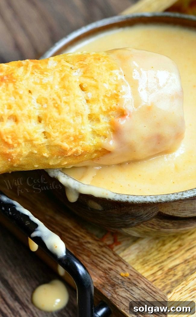 Top view of one Homemade Soft Pretzel after the end was dipped into the bowl of beer cheese dip. The bowl filled with beer cheese dip is underneath the pretzel.