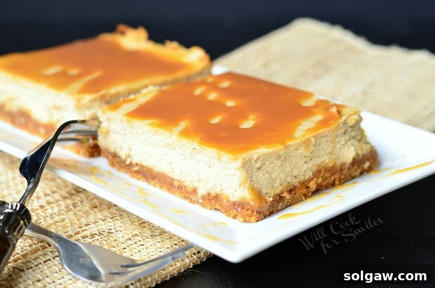 Espresso Caramel Swirl Cheesecake Bars 4 Caramel Macchiato Cheesecake Bars are on a white plate. Caramel is drizzled on top of the bars, as well as on the plate. Forks are criss-crossed to the left side of the plate.