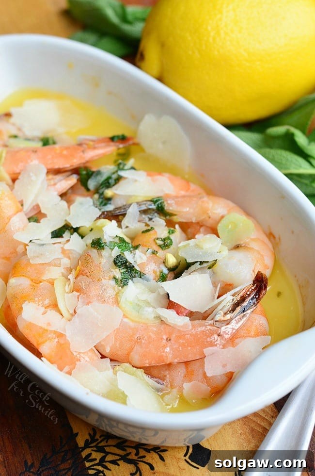 Garlic Sage Butter Shrimp dish in a white baking dish with a lemon on the table beside dish