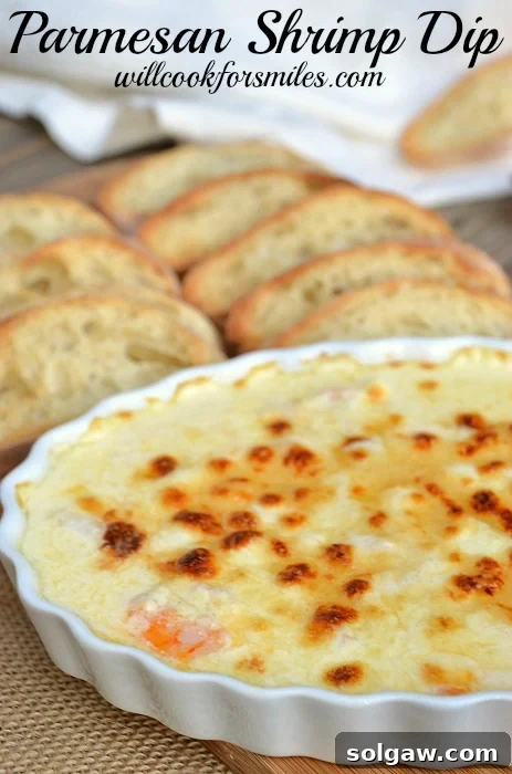 Parmesan shrimp dip in a white baking dish with slices bread behind the bowl on the table