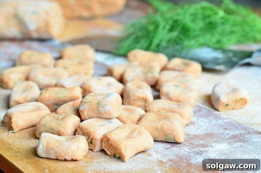 picture of uncooked homemade tomato herb gnocchi on a rolling mat covered lightly in flour