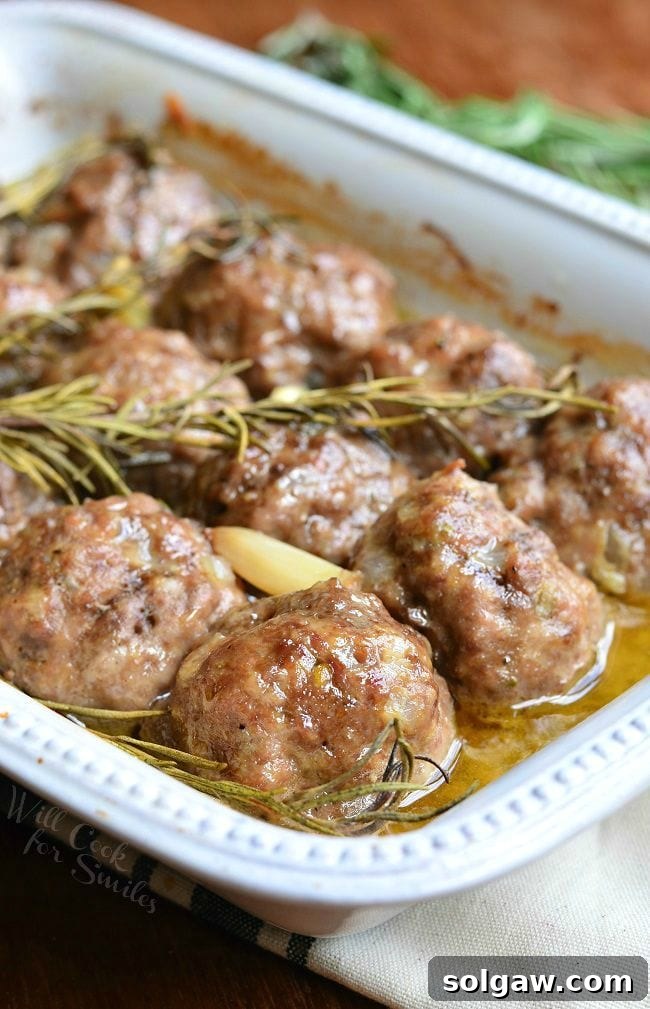 Hearty Meatball Gnocchi Casserole 10 Roasted Garlic Rosemary Baked Meatballs in a white baking dish with fresh garlic and rosemary sprigs