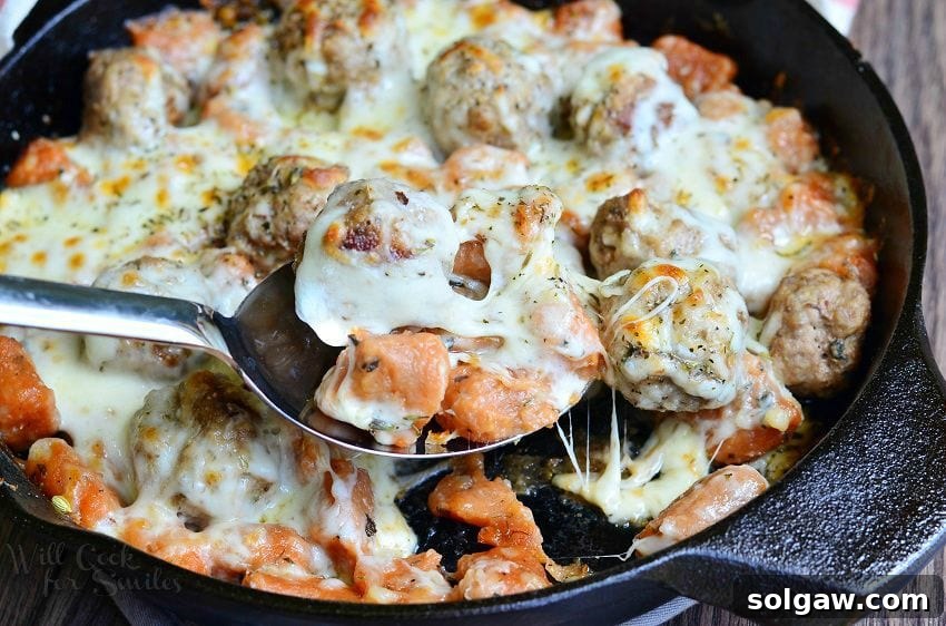 Hearty Meatball Gnocchi Casserole 4 top view of Meatball and Gnocchi Bake in a cast iron skillet with a serving spoon