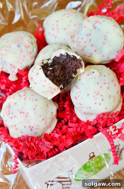 Peppermint Oreo Bites are covered with white chocolate and pink sprinkles with a bite out of one