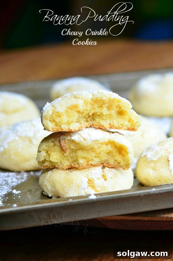 Banana Pudding Chewy Crinkle with one cut in half stacked on top of each other on a cookie sheet