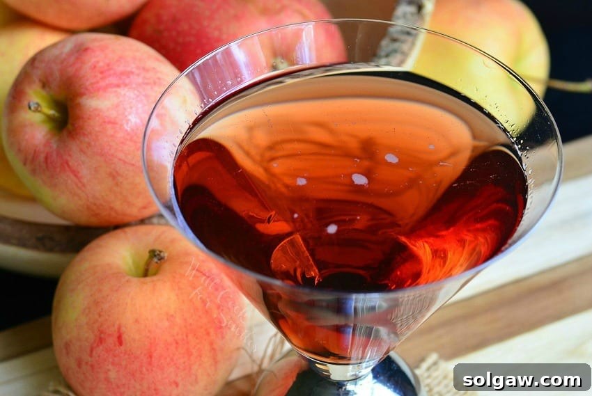 Two Washington Apple Martinis on a wooden surface, with a bowl of red apples in the background, from willcookforsmiles.com