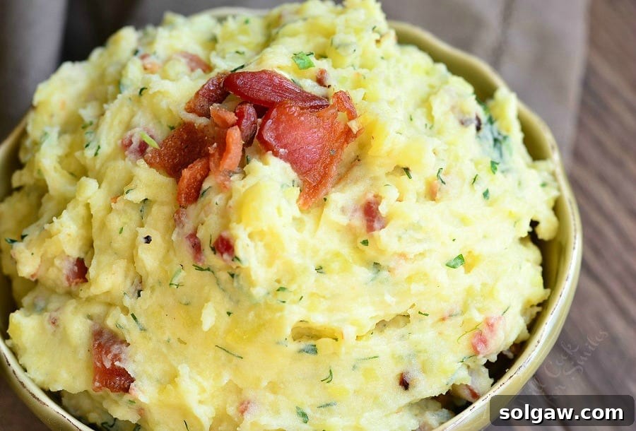 Small decorative bowl filled with creamy bacon and herb mashed potatoes on a wooden table, viewed from above and close up.
