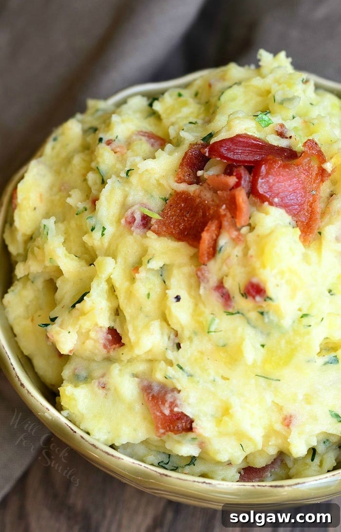 A serving of creamy bacon and herb mashed potatoes in a bowl, showing the intricate mix of flavors and textures.