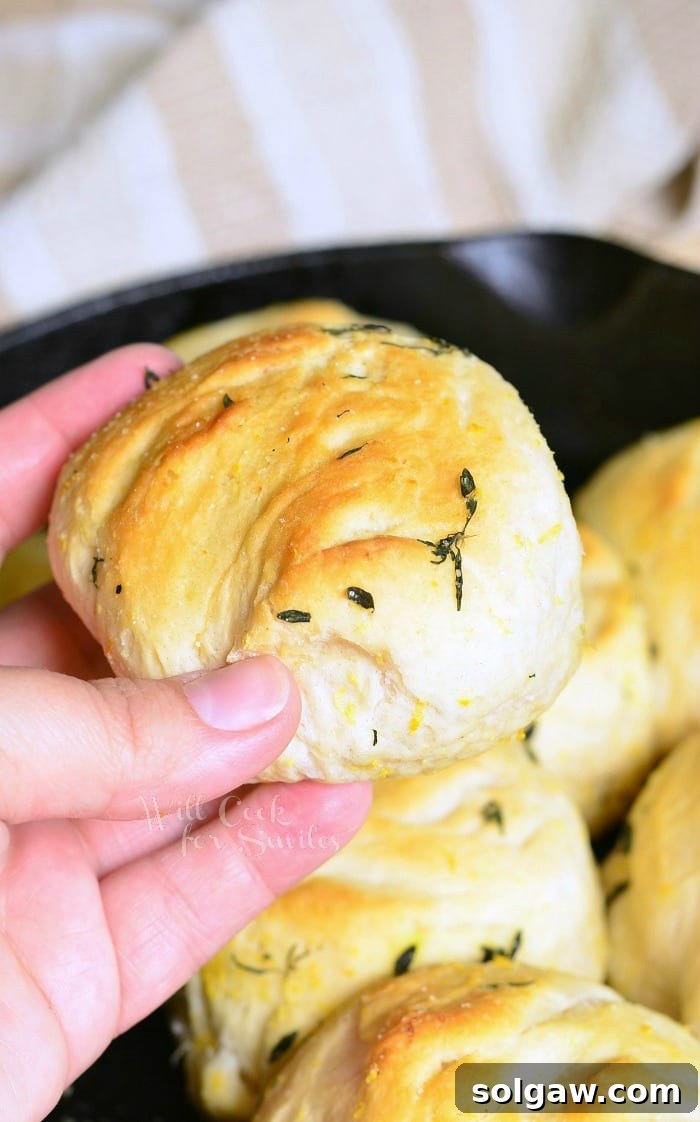 Holding a Biscuit with thyme on it with the rest in a cast iron skillet 